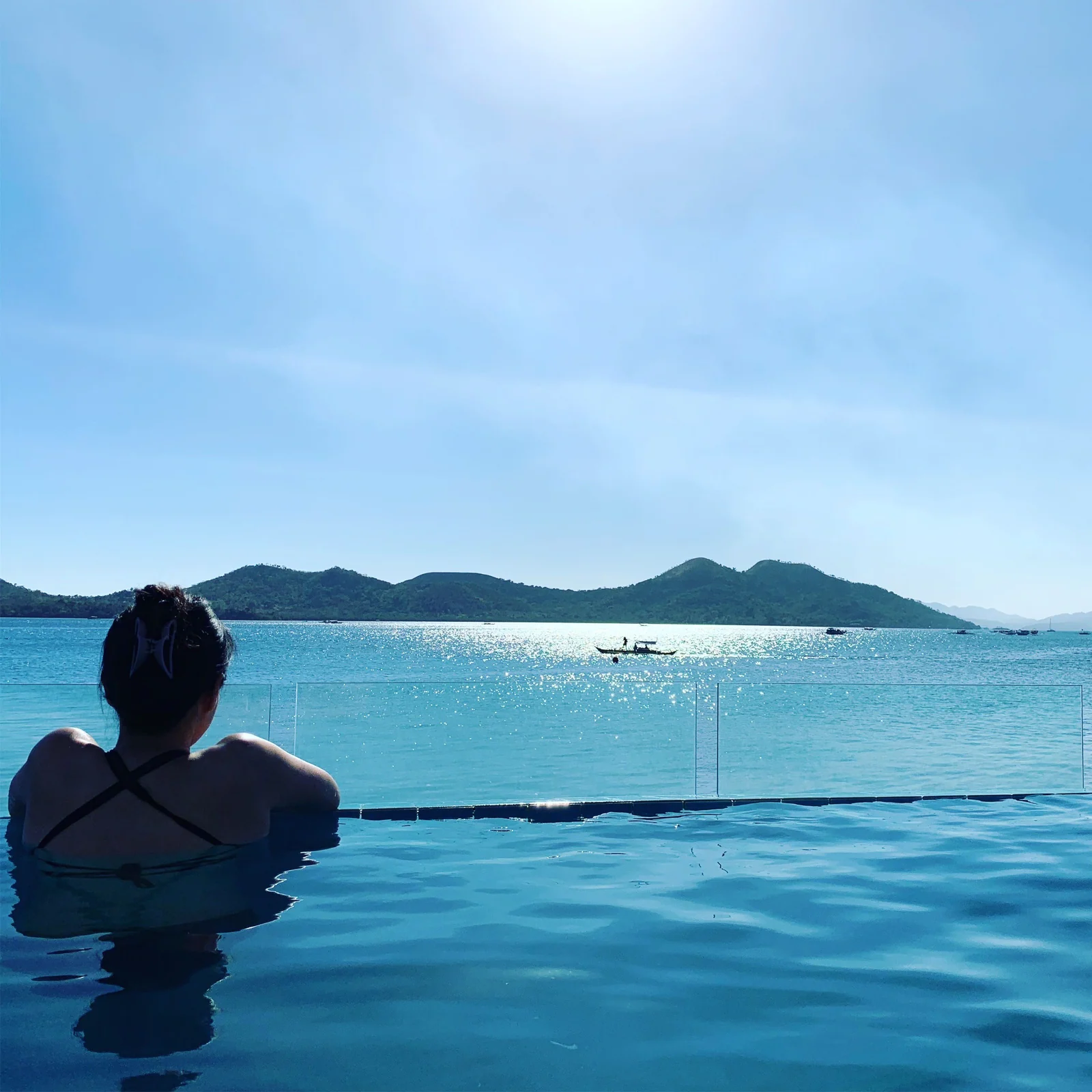 Sunny relaxing in an infinity pool overlooking the sea and islands
